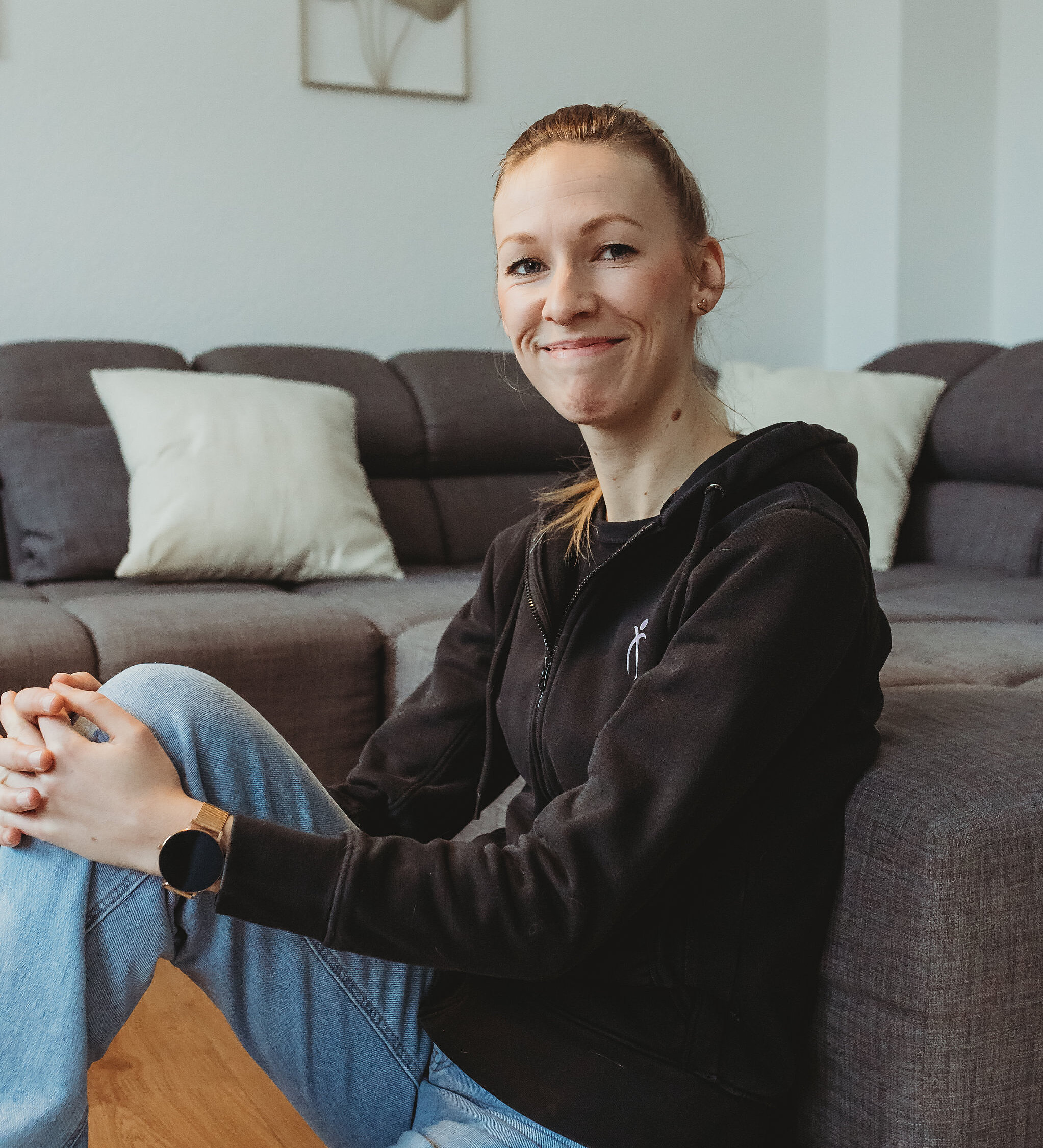 Tierphysiotherapeutin Anna-Lena Heitkötter sitzt auf dem Boden, angelehnt an einem Sofa