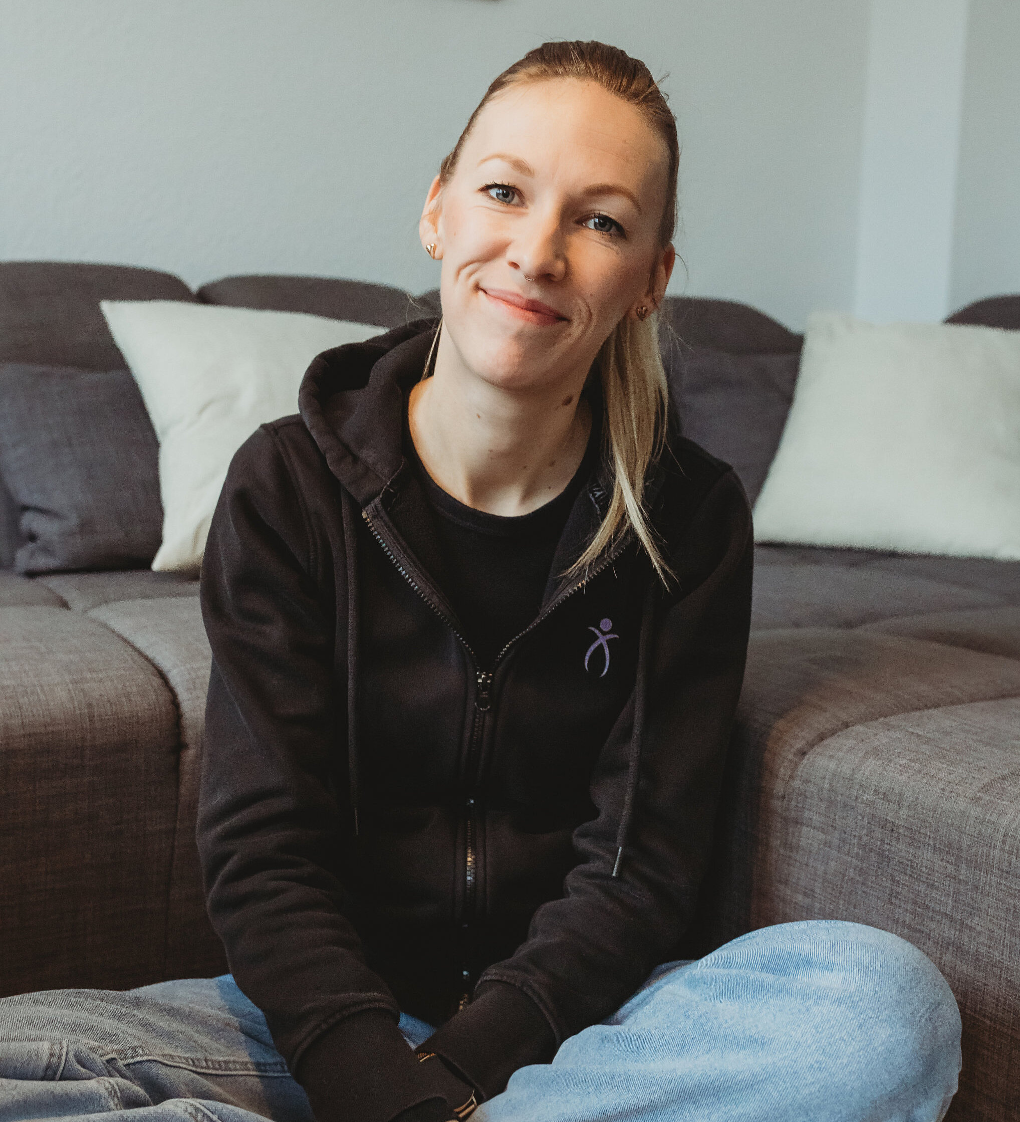 Tierphysiotherapeutin Anna-Lena Heitkötter sitzt lächelnd im Schneidersitz